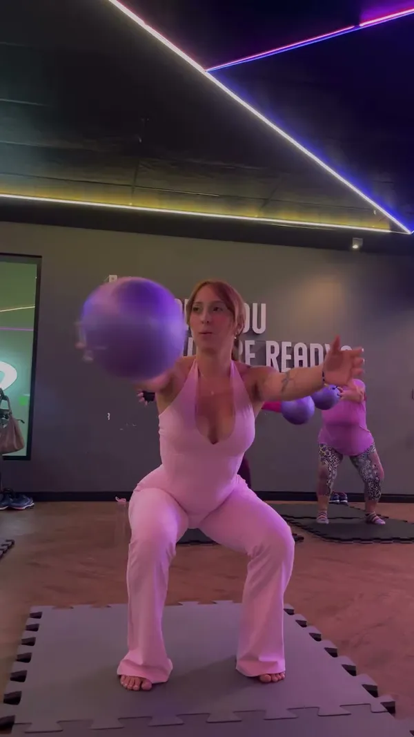 Lara, de roupa rosa, em um momento descontraído durante uma aula de Pilates